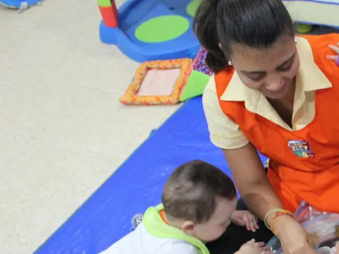Teachers realizando estimulación temprana con bebés sobre una colchoneta