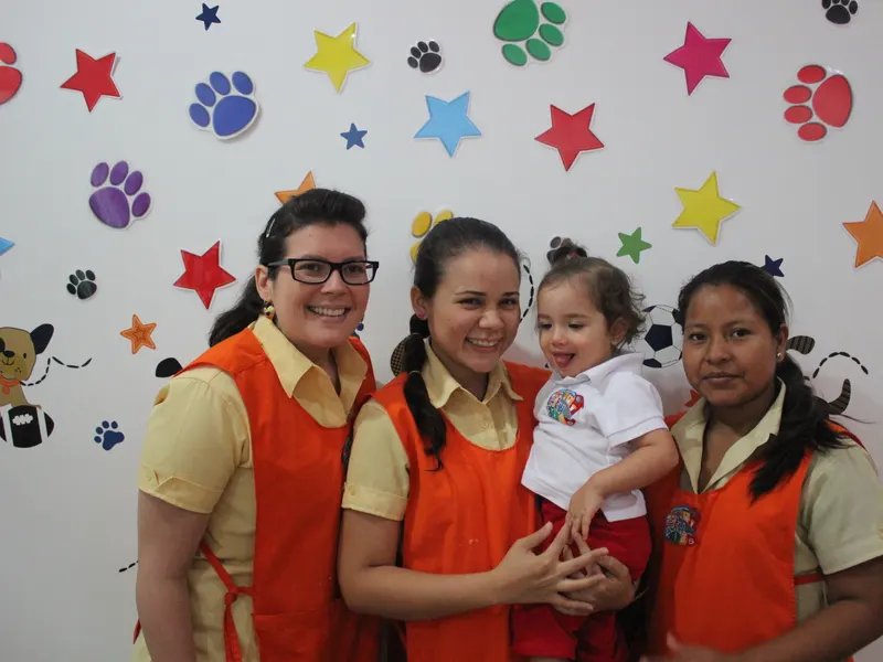 Teachers de Citykids sonriendo junto a una bebé