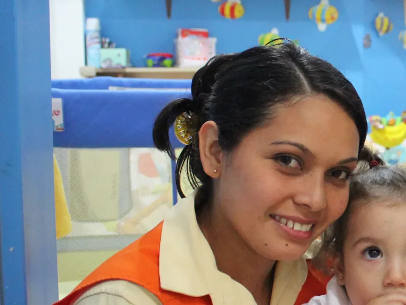 Dos teachers de Citykids sonriendo junto a una bebé
