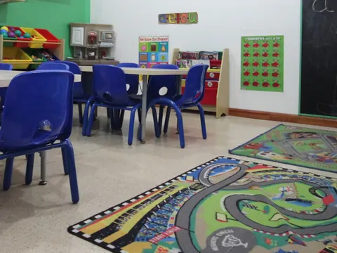 Sala Monkeys con mesas azules, pizarra y alfombra de juego