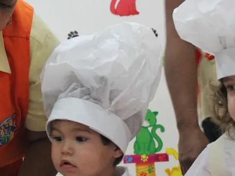 Niños con gorros de chef en un taller de cocina con su teacher